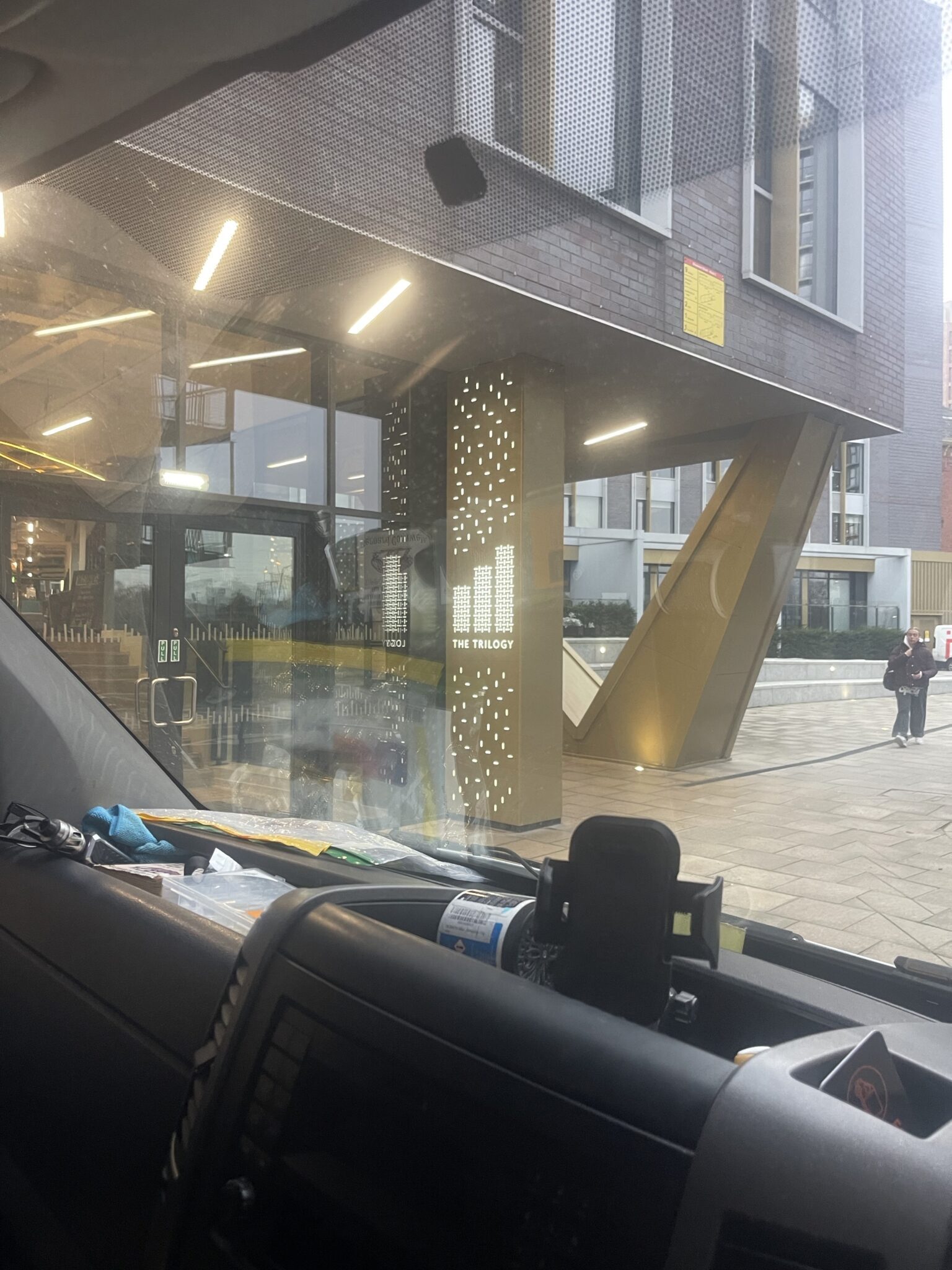 View from inside an ESV Removals van outside The Trilogy apartment building entrance, showing a managed block where lift booking and floor protection help prevent mud or rain being tracked inside.