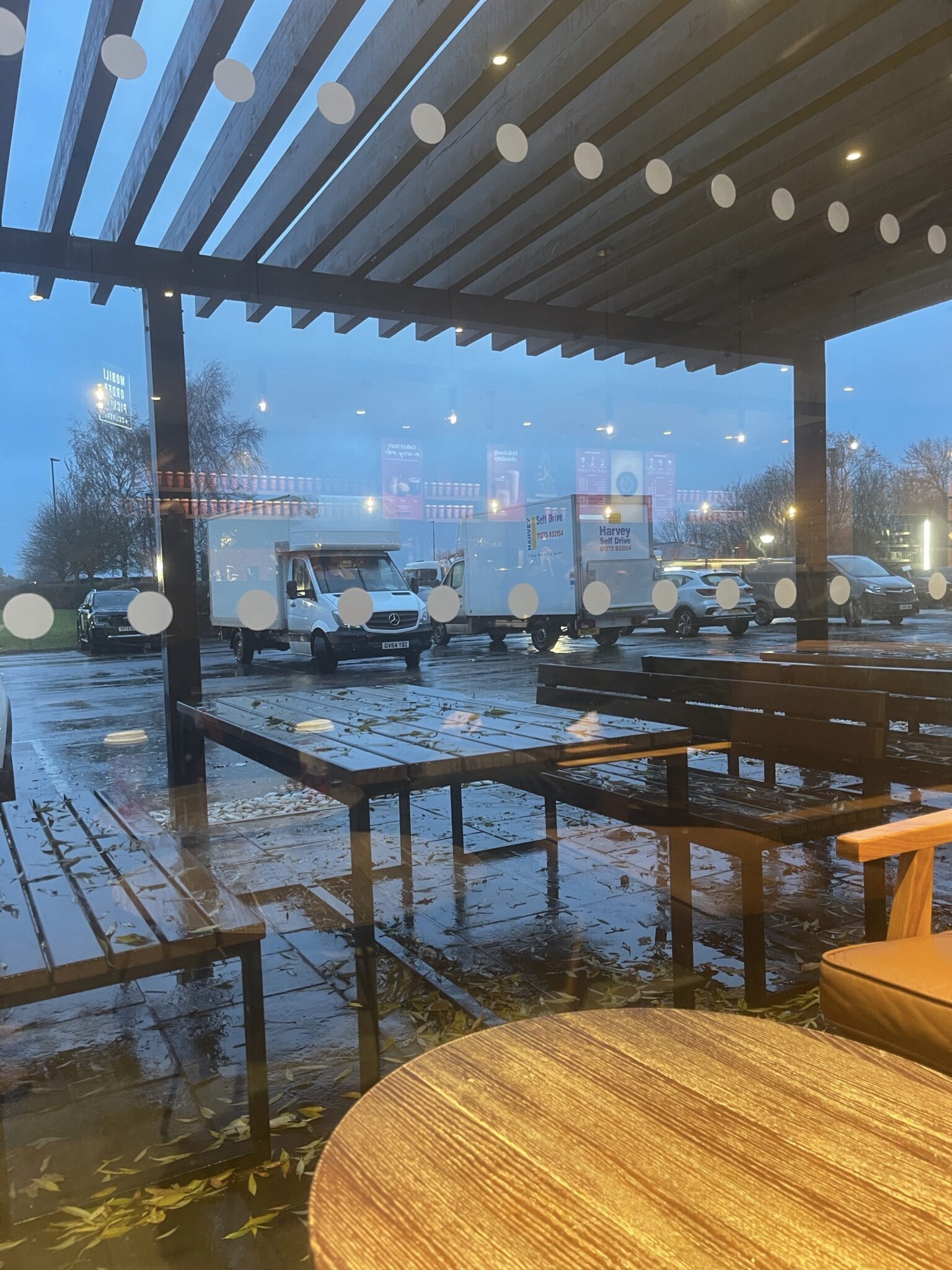 View from a service station café showing ESV Removals Luton vans parked outside in the rain during a long distance Brighton to Edinburgh house move.